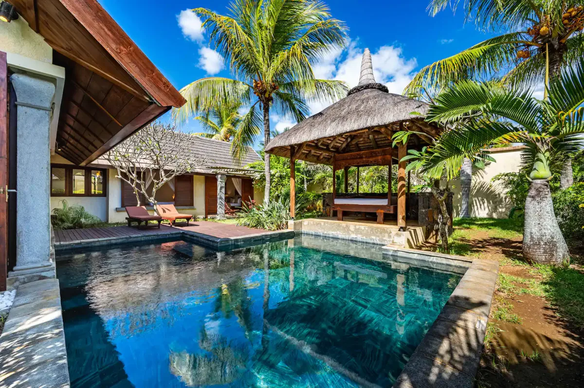 The villa: a thatched gazebo beside a private pool ringed by palms